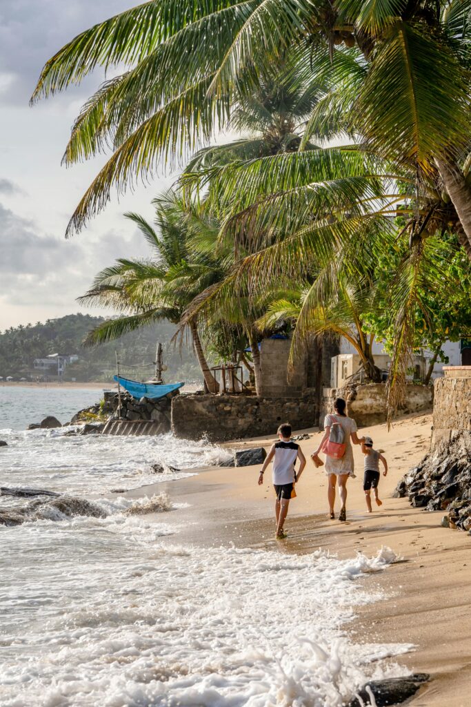A family enjoys a walk along the palm-lined shores of Unawatuna Beach, Sri Lanka.